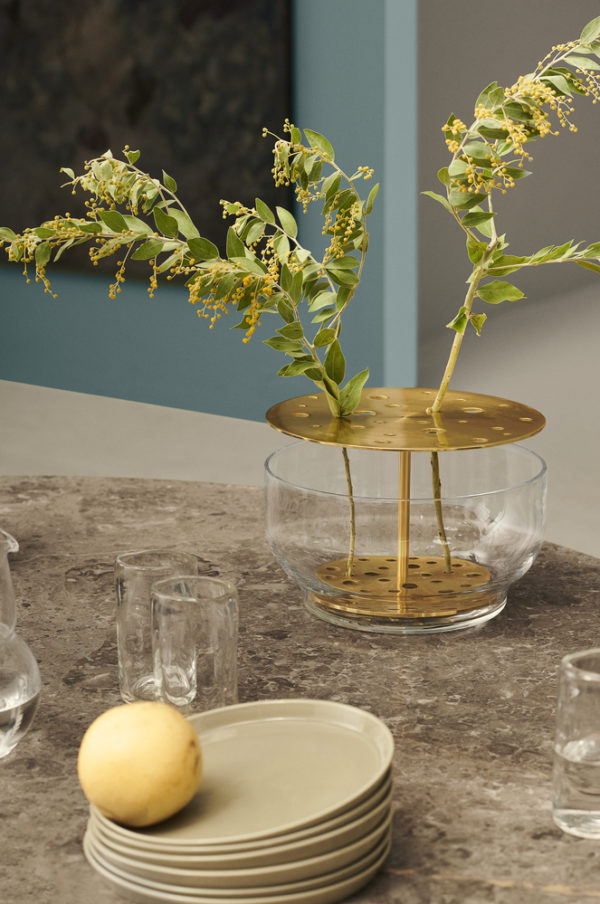Die Vase hebt jede jeder einzelnen Blume hervor, vom Stiel bis zur Blütenkrone und ist in rostfreien Stahl oder in Messing erhältlich.