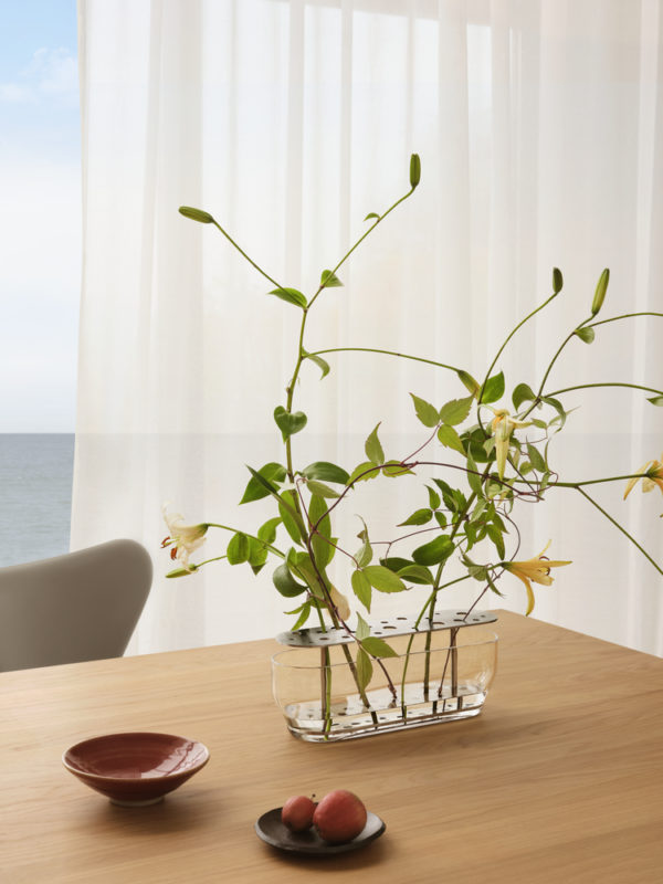 Die Vase hebt jede jeder einzelnen Blume hervor, vom Stiel bis zur Blütenkrone und ist in rostfreien Stahl oder in Messing erhältlich.