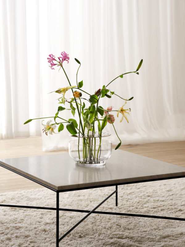 Die Vase hebt jede jeder einzelnen Blume hervor, vom Stiel bis zur Blütenkrone und ist in rostfreien Stahl oder in Messing erhältlich.