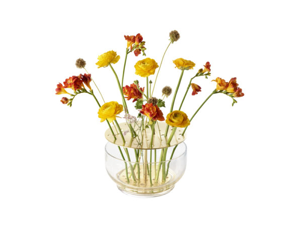 Die Vase hebt jede jeder einzelnen Blume hervor, vom Stiel bis zur Blütenkrone und ist in rostfreien Stahl oder in Messing erhältlich.