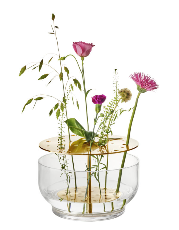 Die Vase hebt jede jeder einzelnen Blume hervor, vom Stiel bis zur Blütenkrone und ist in rostfreien Stahl oder in Messing erhältlich.