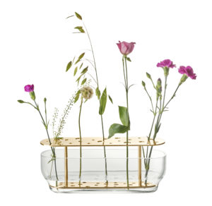 Die Vase hebt jede jeder einzelnen Blume hervor, vom Stiel bis zur Blütenkrone und ist in rostfreien Stahl oder in Messing erhältlich.